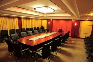 Un salón de conferencias con una larga mesa, varias sillas y una pantalla para proyector.