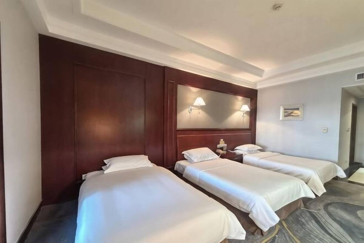 Une chambre d’hôtel avec deux lits, un grand miroir et une table de chevet avec une lampe.