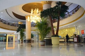 Un hall d’entrée spacieux, agrémenté d’un magnifique lustre, de palmiers et d’un comptoir d’accueil.