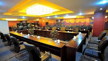 A conference room with multiple tables and chairs, equipped with a projector screen and a whiteboard.
