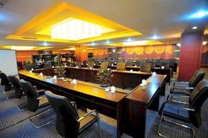 A conference room with multiple tables and chairs, equipped with a projector screen and a whiteboard.