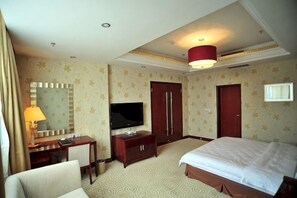 Een hotelkamer met een bed, een bureau met een televisie, een kledingkast en een spiegel.