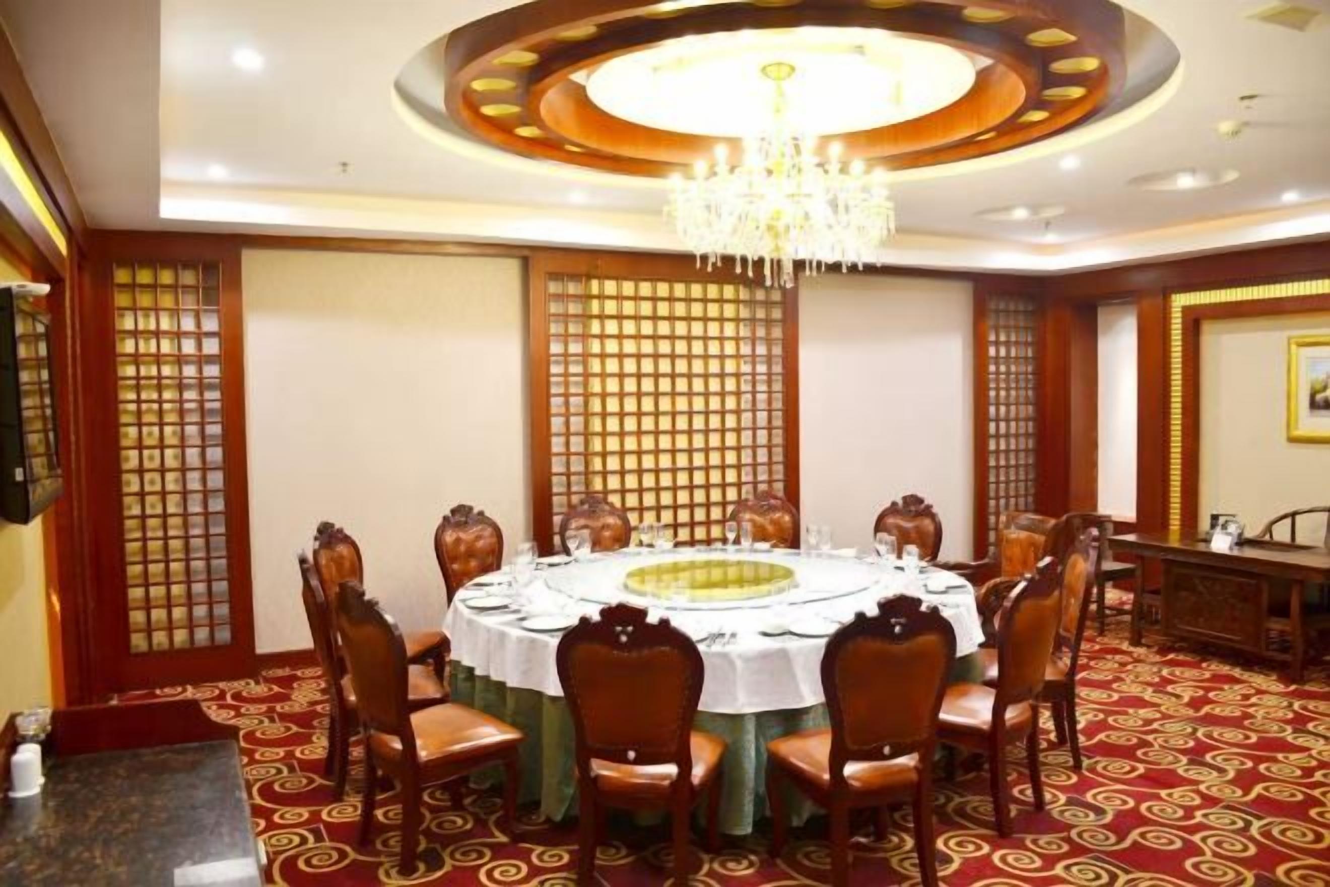 A conference room with a round table, chairs, and a chandelier.