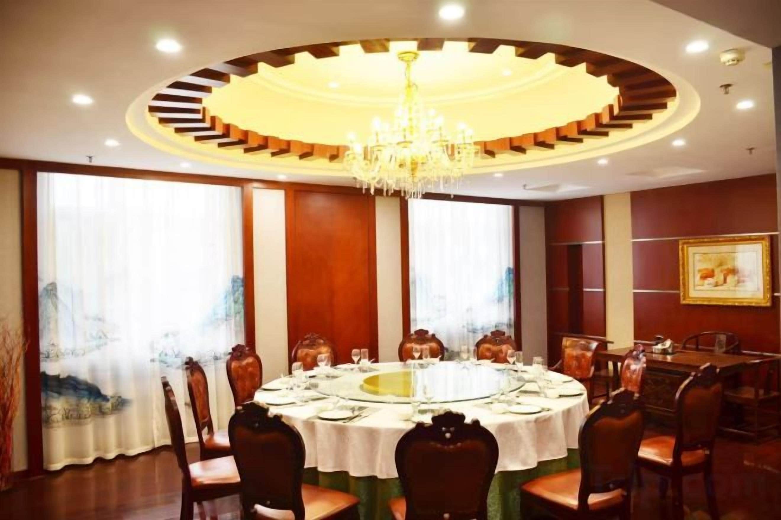 Un comedor con una mesa redonda, sillas y una araña.
