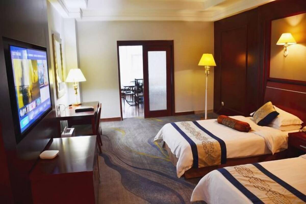 Une chambre d’hôtel avec deux lits, une télévision, un bureau et une chaise.