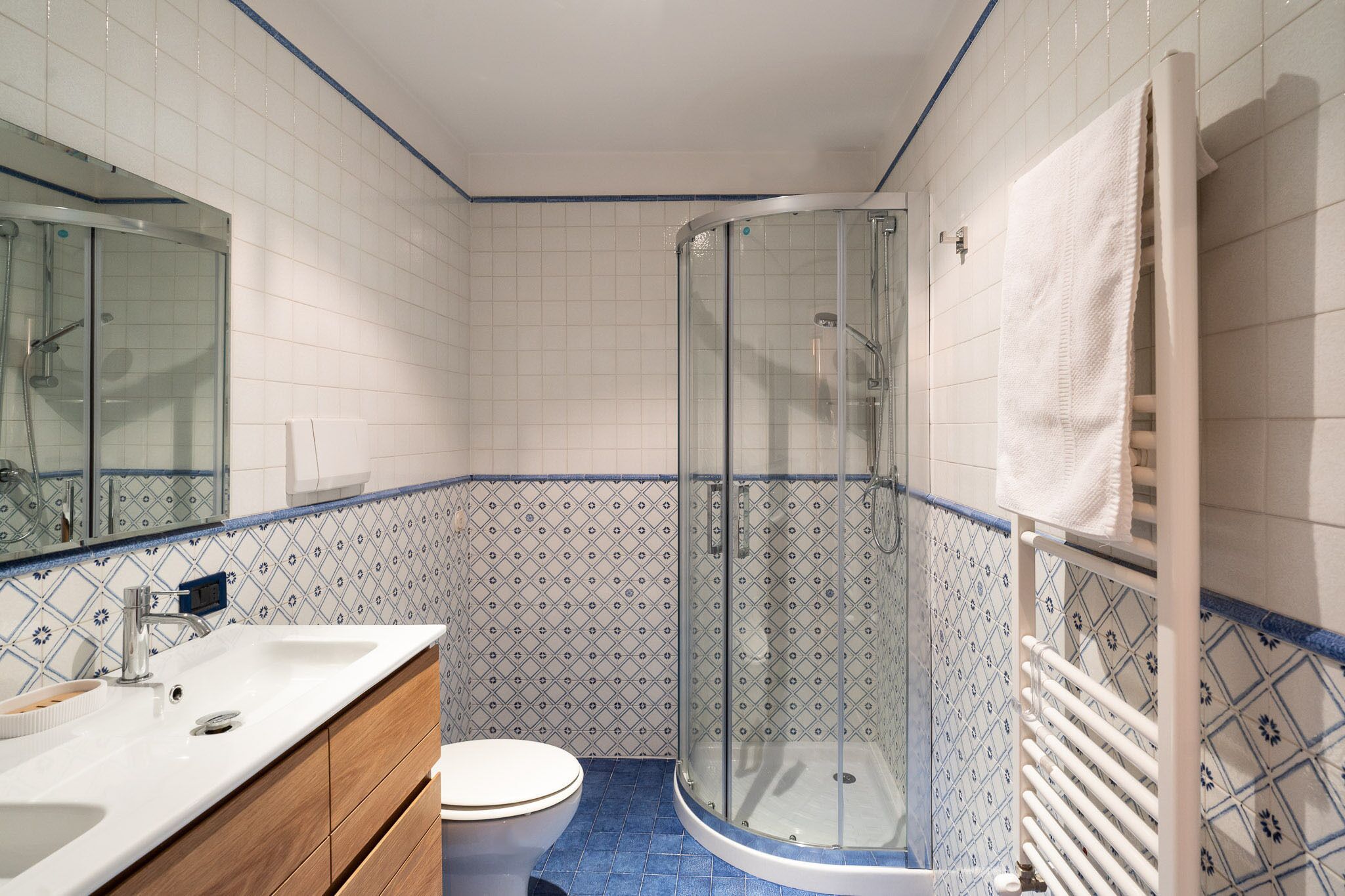 A bathroom with a glass-enclosed shower, a sink, and a toilet.