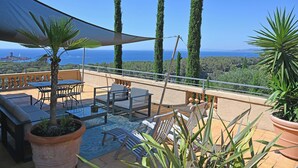 A terrace with a table and chairs, a potted plant, and a view of the sea. - VILLA ALFONSA, Apartment "LA TERRASSE" exceptional sea view, 1st floor. (Saint-Raphaël Agay)