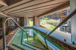 Un espace avec un bain à remous offrant une vue sur une colline et un bâtiment en arrière-plan.