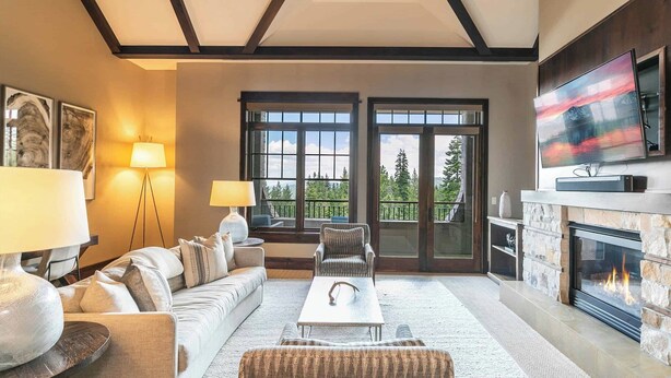A modern living room with a fireplace, large windows, and a cozy seating area.