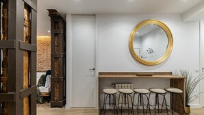A modern bar area with a round mirror, wooden stools, and a brick wall in the background.