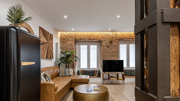 A modern living room with a leather sofa, a round coffee table, and a flat-screen TV.