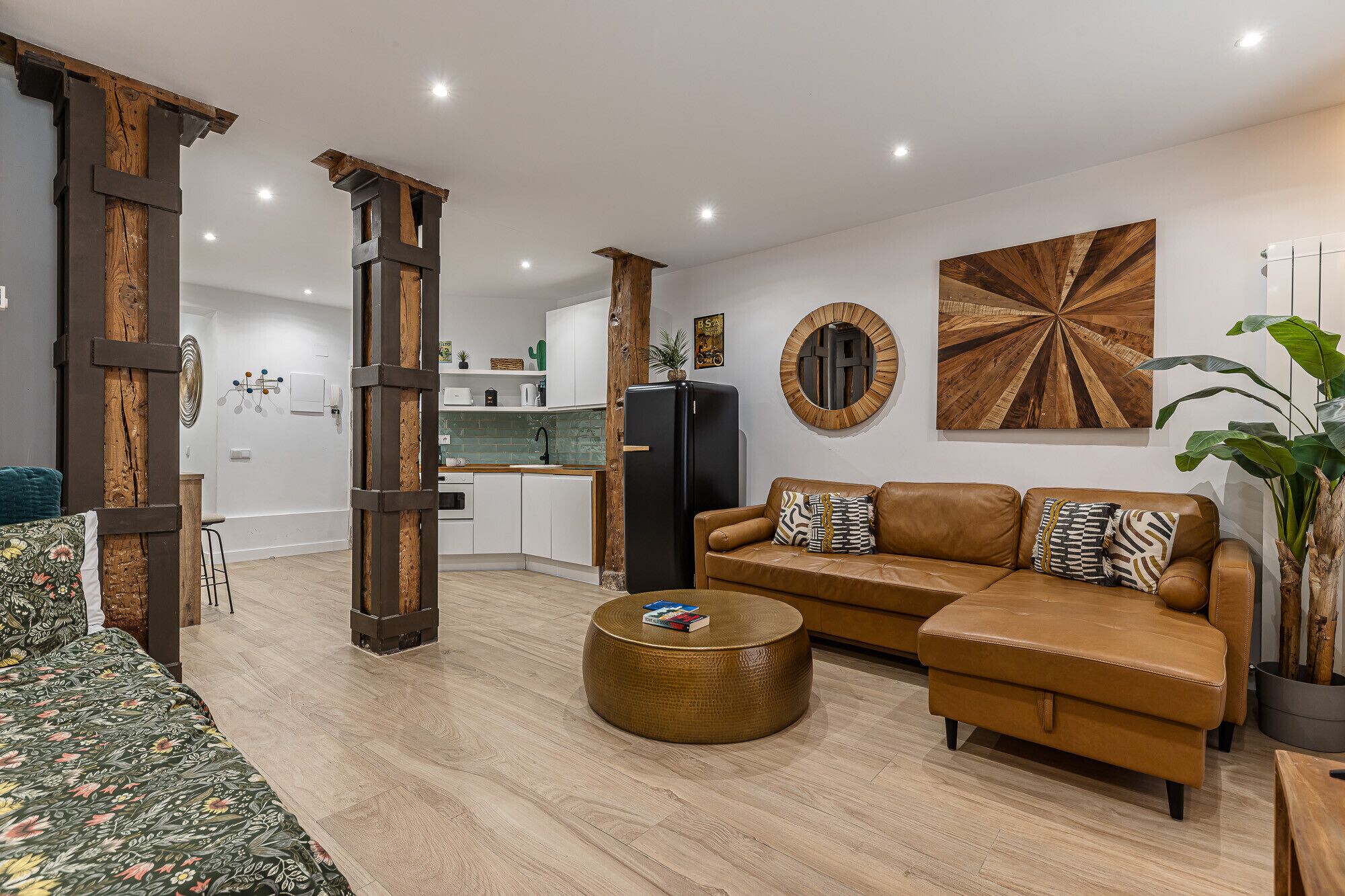 Una sala moderna con sofá, mesa de centro y comedor, con cocina al fondo.