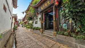 A traditional Chinese courtyard with stone paving, wooden architecture, and lush greenery. - Weaving Sunshine Vacation Designer Ancient City View Garden Hotel (the Old Town of Lijiang) (Lijiang)