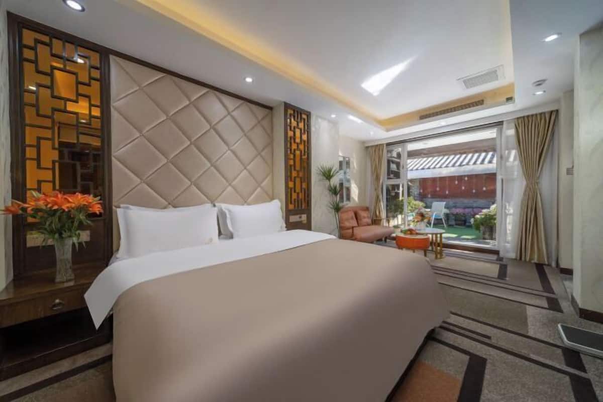 A hotel room with a bed, a desk, a chair, a window with curtains, and a view of the outside.