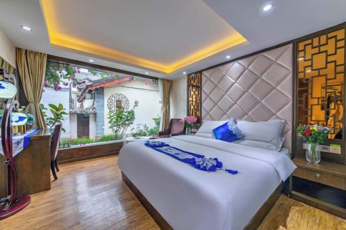 A hotel room with a large bed, a desk, and a view of the outside.