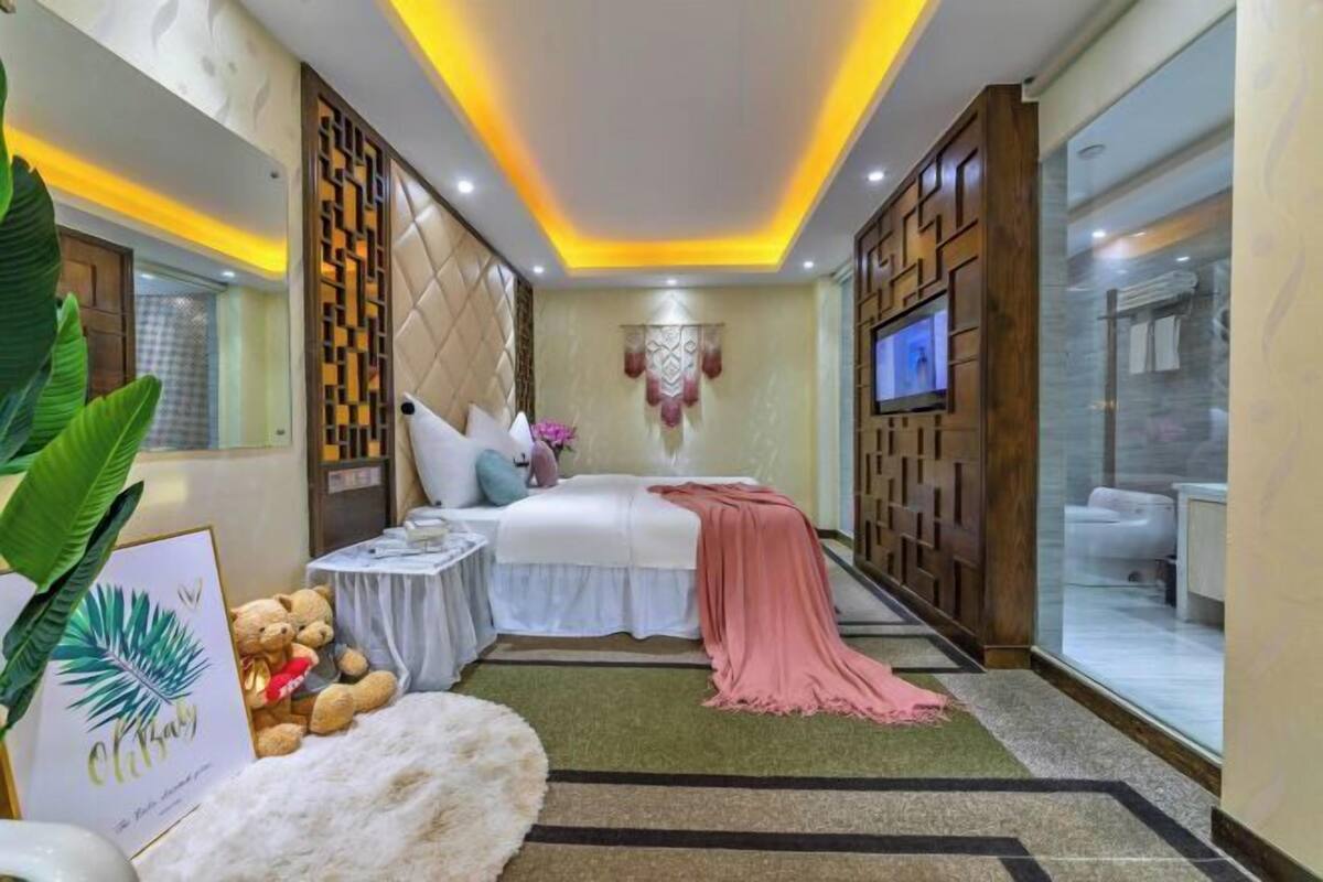 A bedroom with a bed, bedside table, and a decorative wall panel.