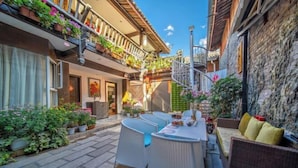 A courtyard with a dining area, wicker furniture, and potted plants. - Weaving Sunshine Vacation Designer Ancient City View Garden Hotel (the Old Town of Lijiang) (Lijiang)