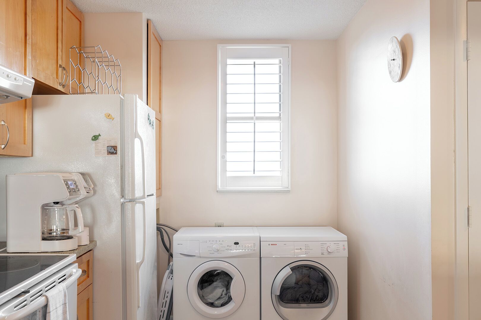 A compact kitchen with a refrigerator, coffee maker, and washing machine.