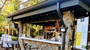 Ett utomhusområde med bar, där väggarna är klädda med sten, och som har en menytavla och möbler av rotting.