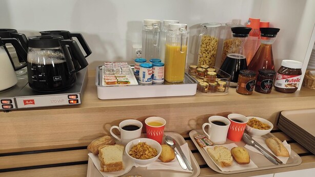 Montaje de un bufé de desayuno con café, jugo, cereales y condimentos.