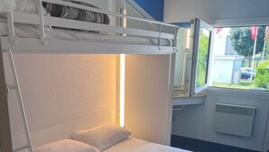Una cama litera con ropa blanca y una ventana que da a vistas del exterior.