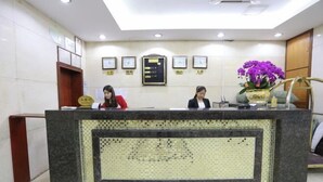 A reception desk with a mosaic design, framed certificates on the wall, and a potted plant. - Fu Gang Hotel (Guangzhou)