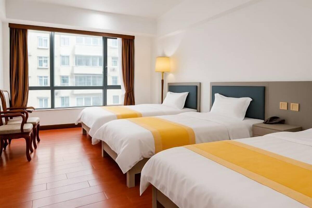 Una habitación de hotel con tres camas, un escritorio y una silla.