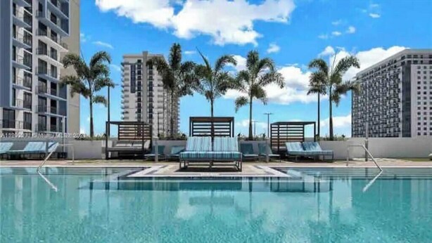 A swimming pool with lounge chairs and palm trees. - A705A Awesome DT Doral Apart
 (Doral)