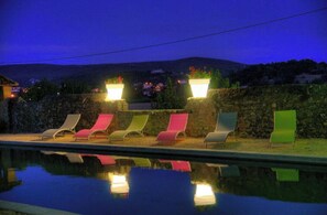 Relax by the pool with lounge chairs positioned on a stone wall, surrounded by a serene landscape.