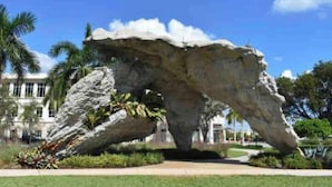 Una gran formación rocosa en un área ajardinada, con un edificio al fondo.