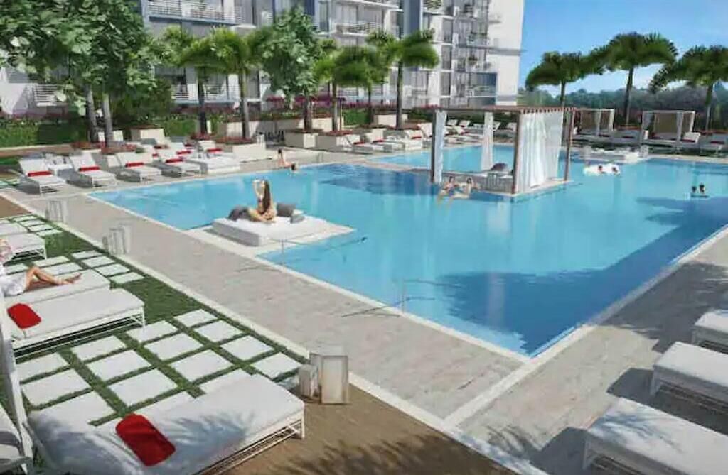 A swimming pool with lounge chairs and palm trees.