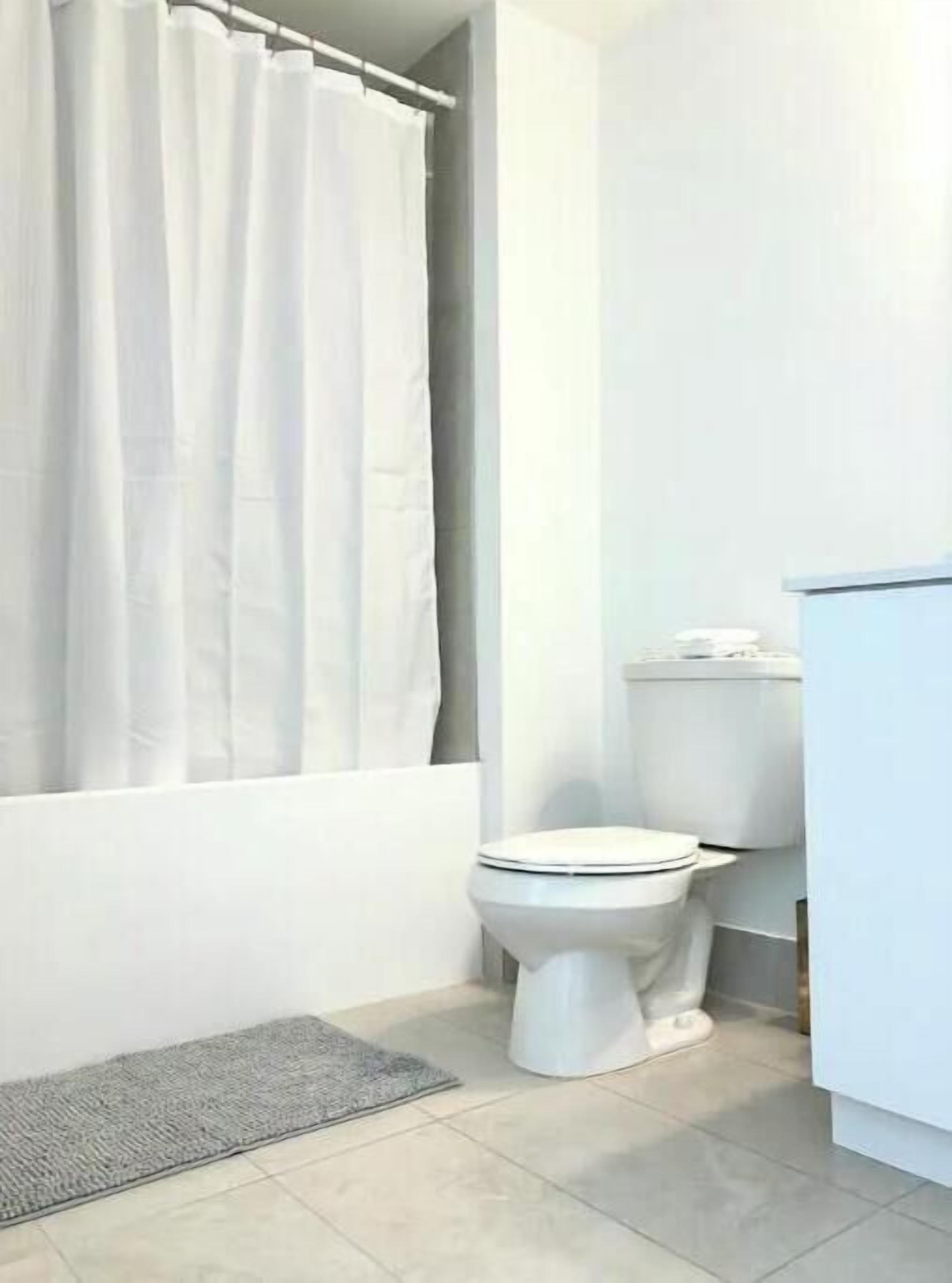 Une salle de bain avec des toilettes, un rideau de douche et un tapis.