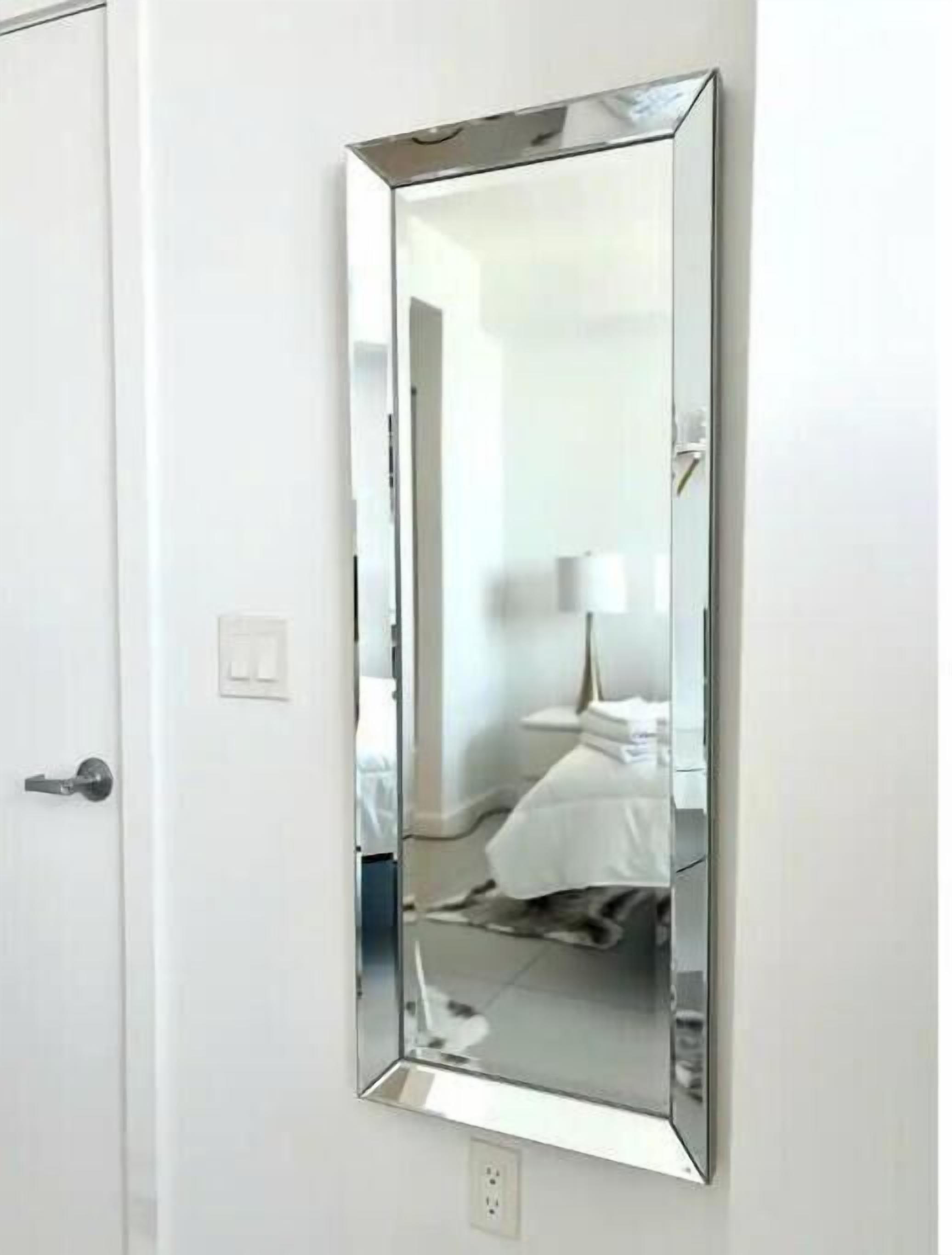 Espejo rectangular sujeto a una pared blanca en una habitación de hotel.