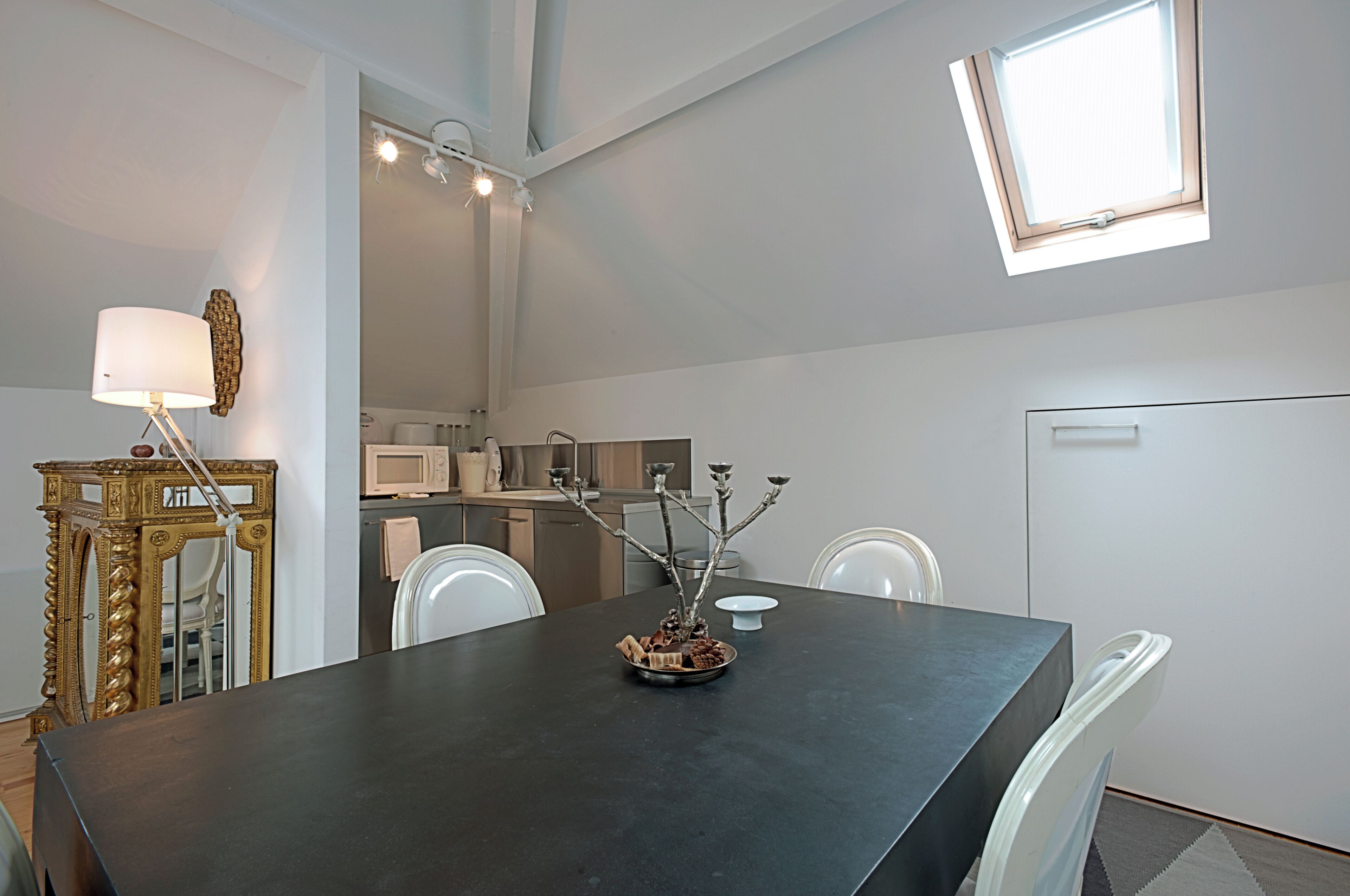 Una cocina moderna con electrodomésticos blancos, una mesa de comedor con sillas y una menorá decorativa sobre la mesa.