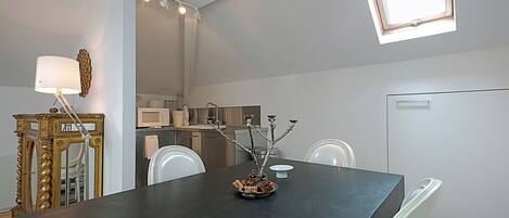 Una cocina moderna con electrodomésticos blancos, una mesa de comedor con sillas y una menorá decorativa sobre la mesa.