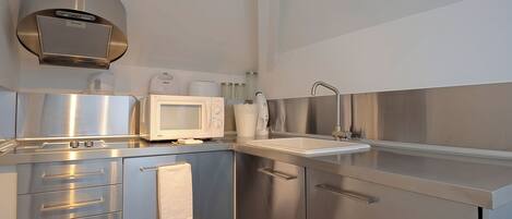 A modern kitchen with stainless steel appliances, a microwave, a coffee maker, and a sink.