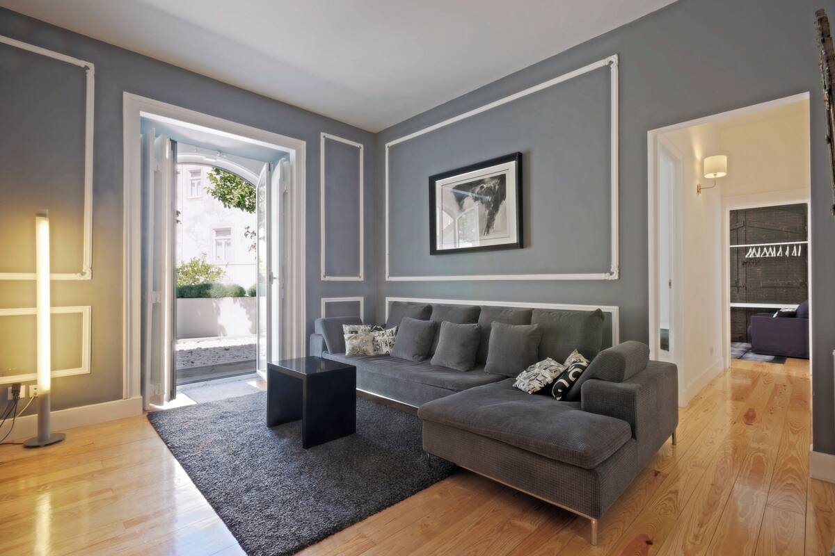 A modern living room with a grey sofa, a black coffee table, and a framed picture on the wall.