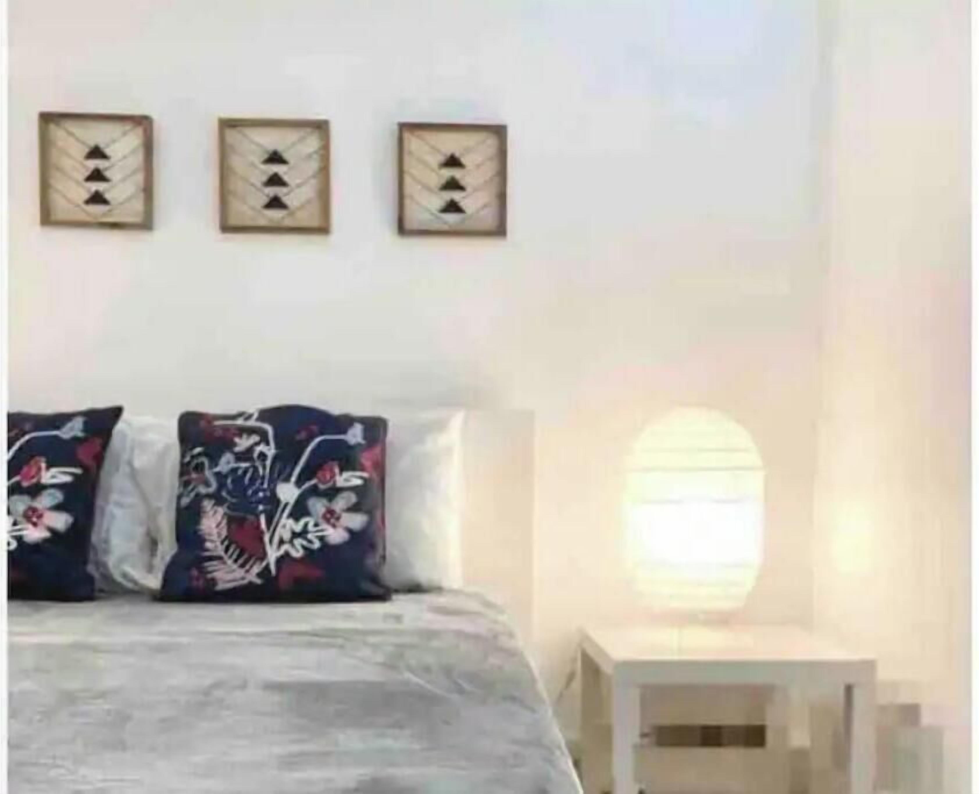 A bedroom with a bed, pillows, a nightstand, and wall art.