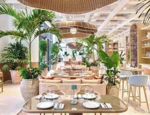 A spacious indoor area with a dining table set for two, surrounded by comfortable seating and large potted plants. - Cozy 1/1 Apartment in the heart of Coconut Grove (Miami)