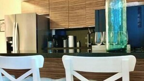 Una cocina moderna con armarios de madera, encimera negra y taburetes blancos.
