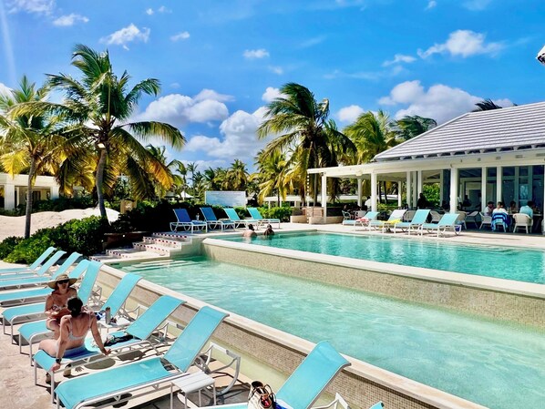 A pool area with lounge chairs and a covered seating area.