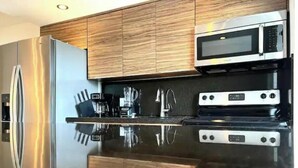 Una cocina moderna con electrodomésticos de acero inoxidable, armarios de madera y una encimera reflectante.