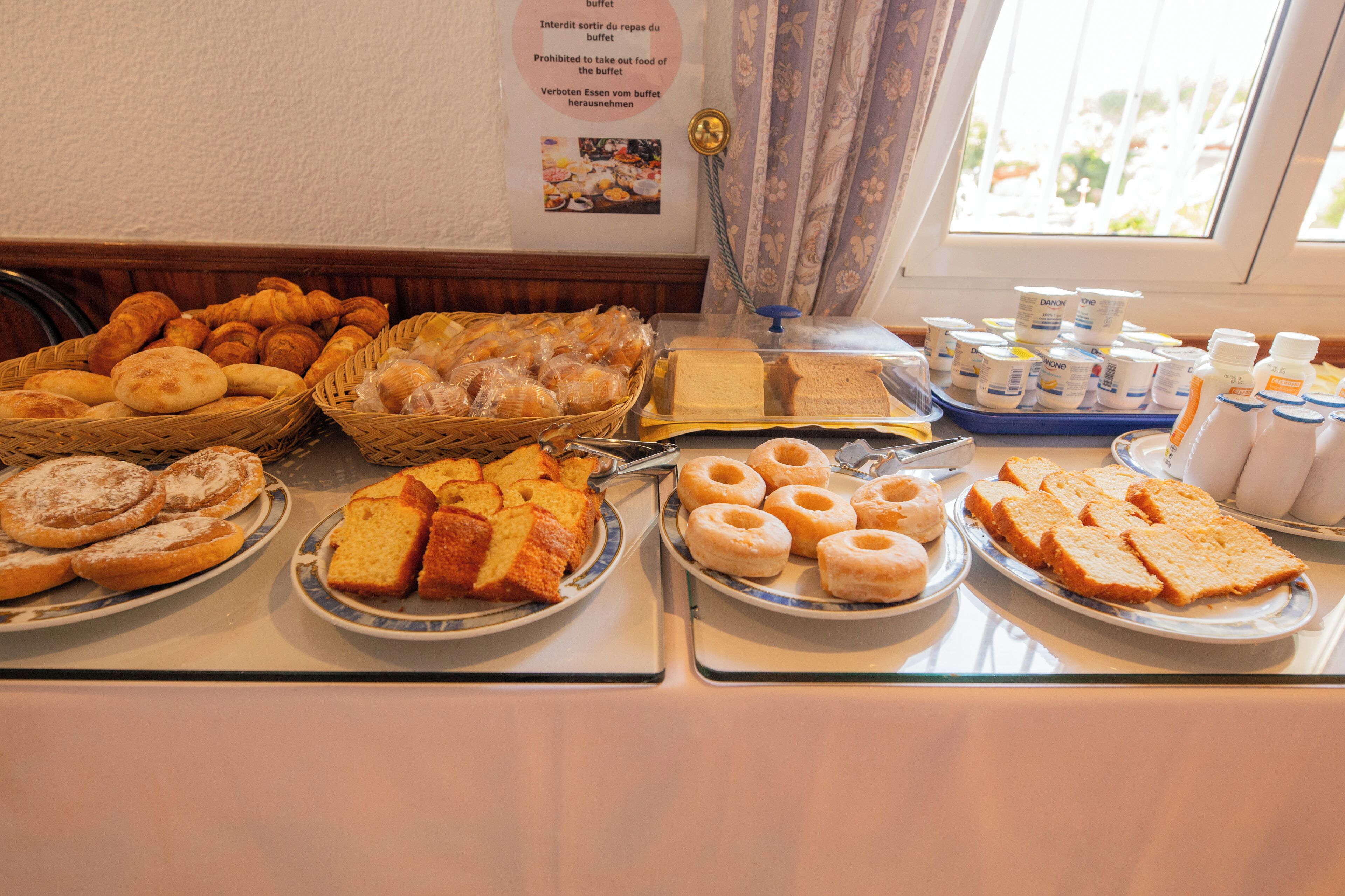 A buffet with various food items including pastries, bread, and beverages.