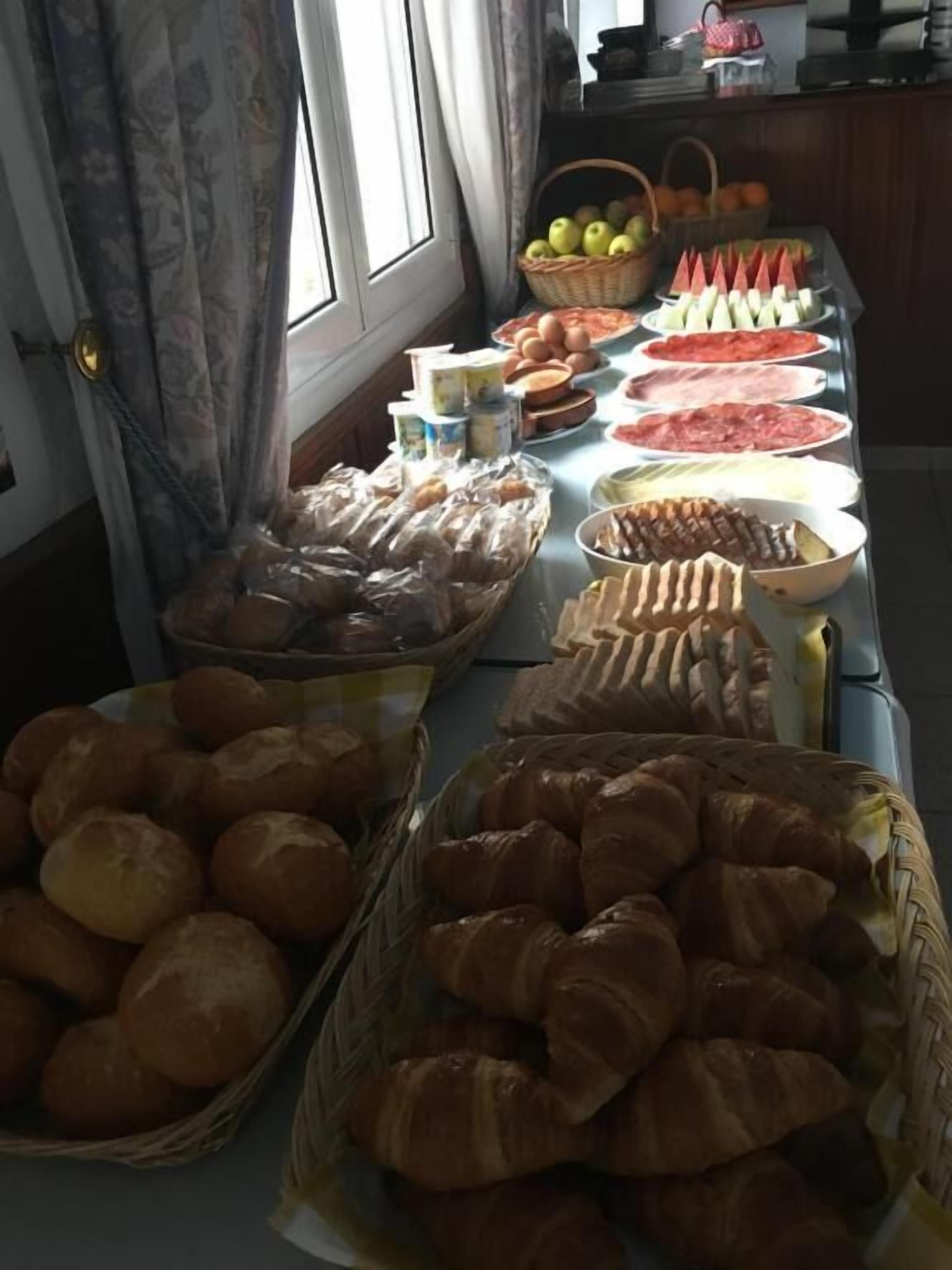A buffet table with various food items including bread, pastries, and fruits.