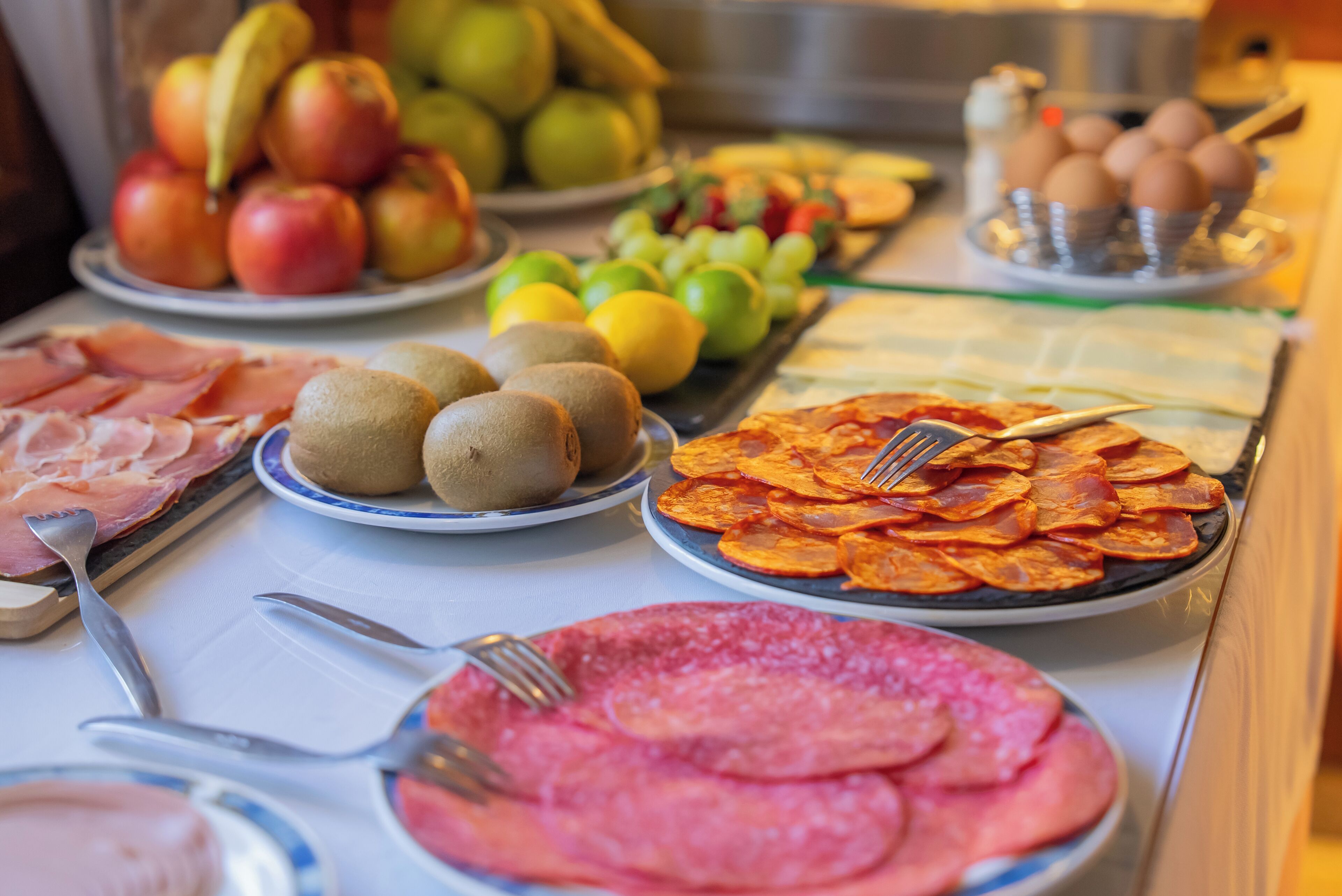 A buffet table with various food items including fruits, meats, and vegetables.