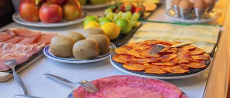 A buffet table with various food items including fruits, meats, and vegetables.