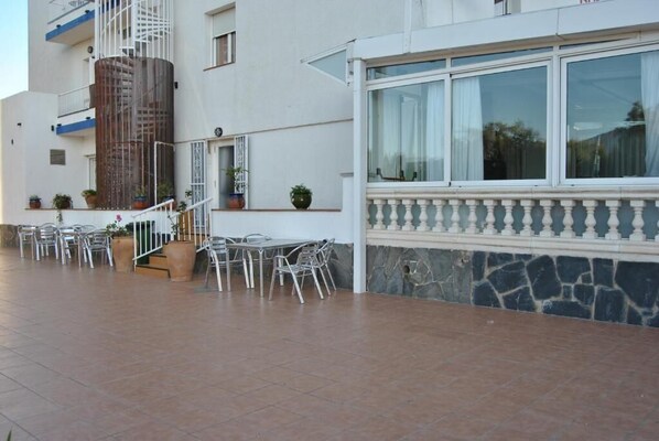 A building with a terrace area featuring outdoor seating and potted plants. - Hotel Montana by Bossh (Roses)