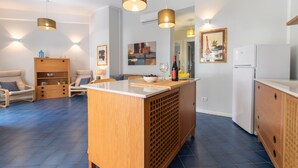 A modern kitchen with a central island, pendant lighting, and a dining area with chairs. - Villa Makar Sea View (San Vito Lo Capo)