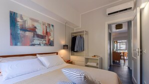 A hotel room with a large bed, a wardrobe, a mirror, and a painting on the wall. - Villa Makar Sea View (San Vito Lo Capo)