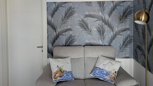 En moderne stue med en grå sofa, dekorative puder, væg med mønster og en gulvlampe.